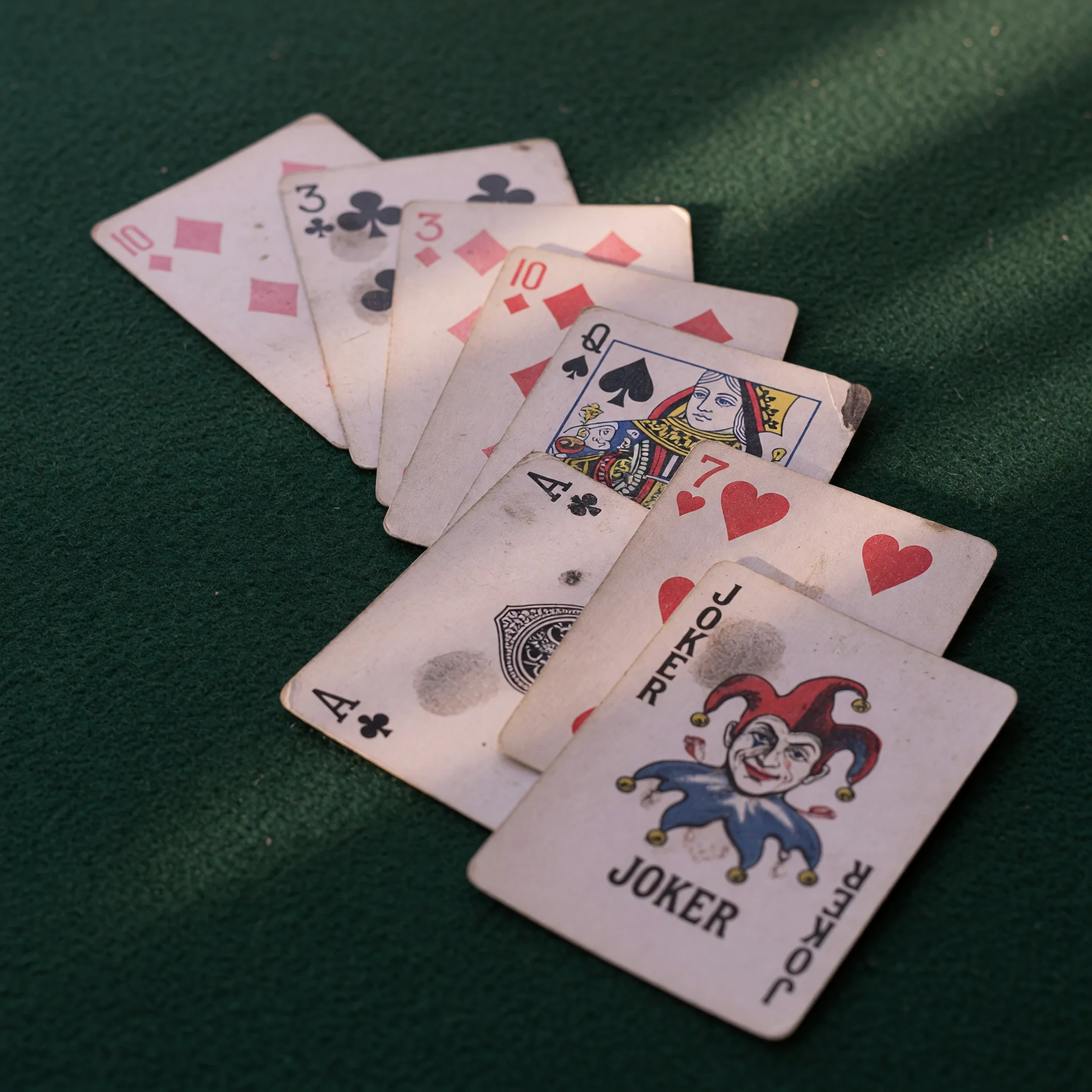 Close-up editorial photograph of an impure sequence with a joker laid out on dark felt