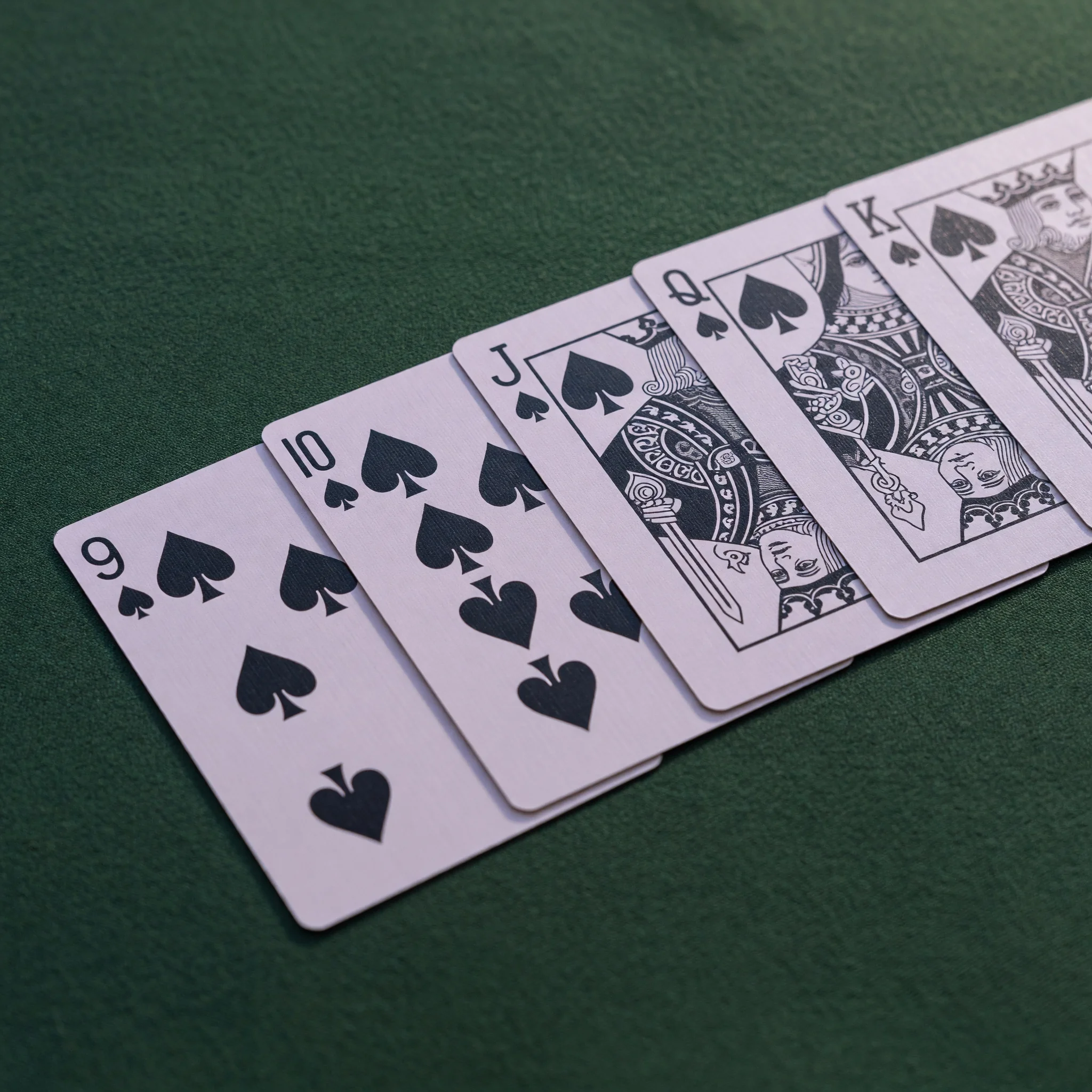 Close-up editorial photograph of a clean pure sequence of spades laid out on dark felt